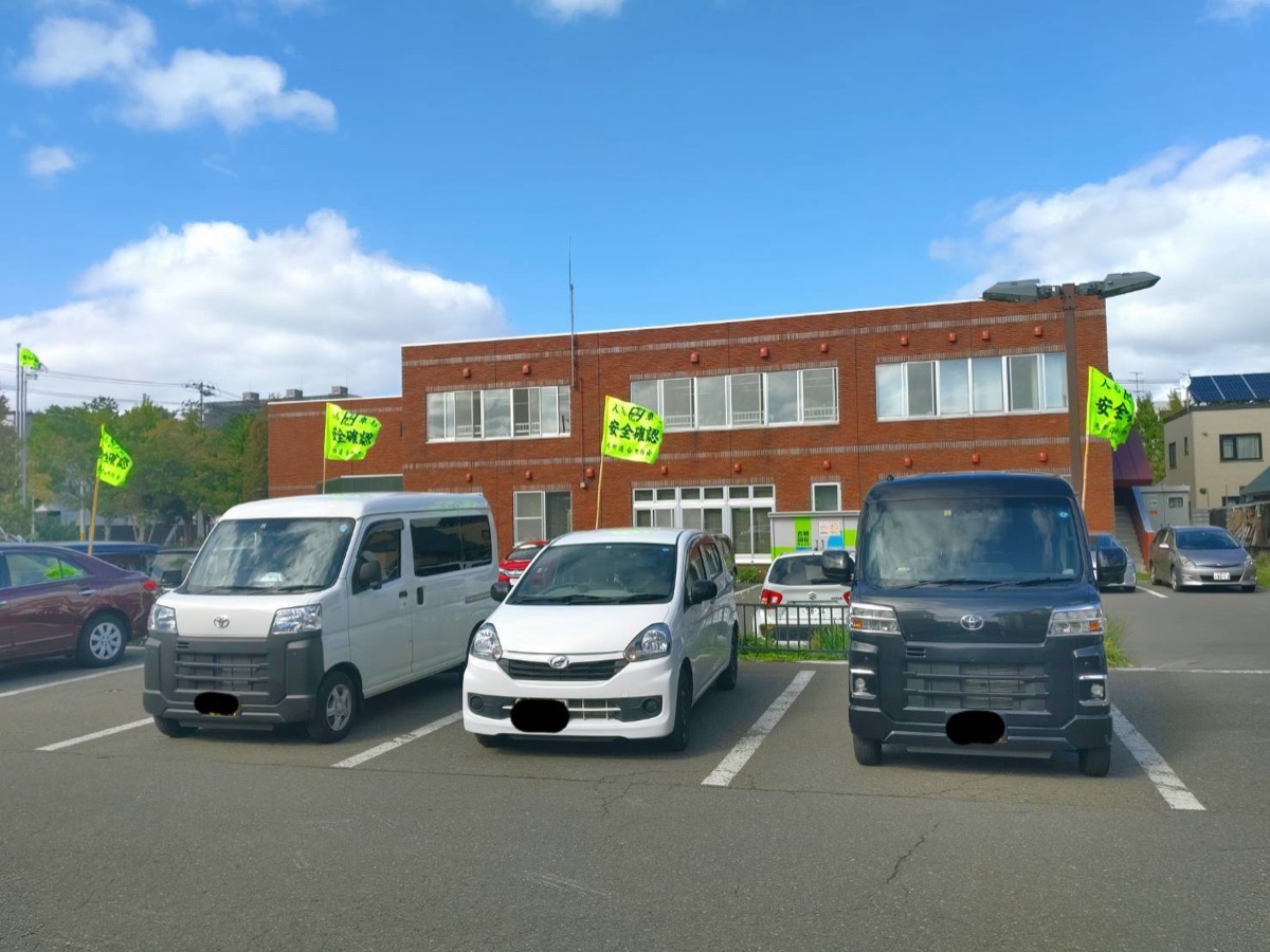 建物前の駐車場に停まる軽自動車3台